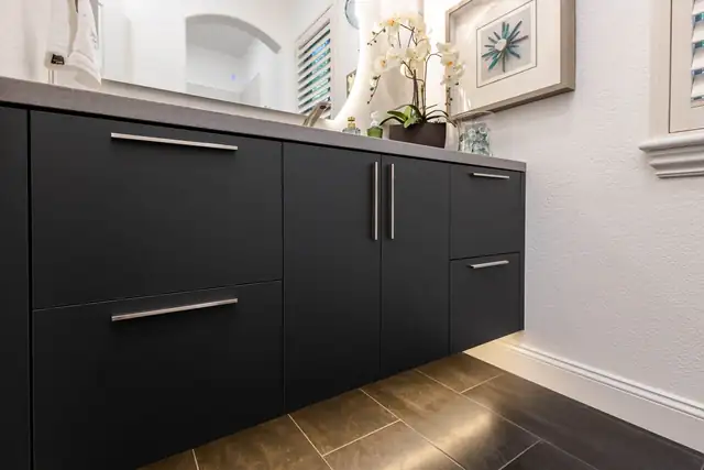 Floating matte black bathroom vanity with long steel pulls and LED strip lighting underneath